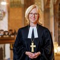 Bischöfin Nora Steen steht im Talar mit Bischofskreuz im Schleswiger Dom, im Hintergrund ist unscharf die Orgel