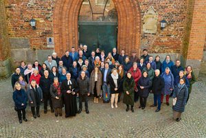 Eine große Gruppe Menschen vor der Tür einer Kirche